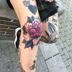 a woman's legs with tattoos on them and flowers in the middle of her leg