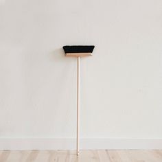 a wooden stick with a black hat on it in front of a plain white wall