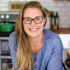 a woman with glasses smiling in a kitchen