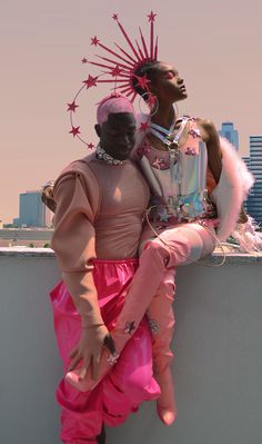 two black women dressed in pink sitting on a wall next to each other with city skyline behind them