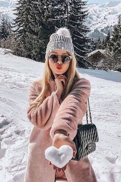 a woman in a pink coat and hat holding a white heart