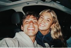 a man and woman taking a selfie in the back seat of a car together