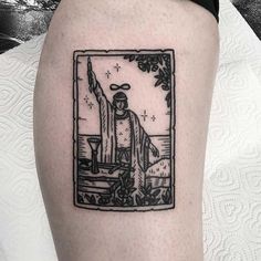 a black and white tattoo on the leg of a person with a statue in the background