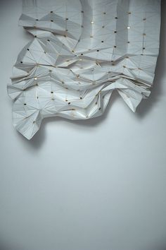 white tissue with gold dots on it hanging from the ceiling in front of a wall