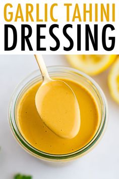 an image of garlic tahini dressing in a glass jar with a spoon on it