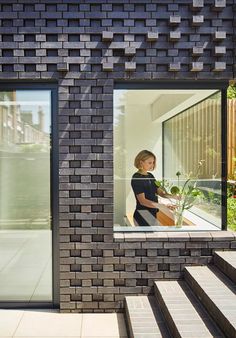 a woman standing in the window of a brick building with stairs leading up to it