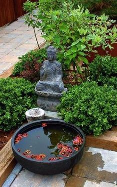 a buddha statue sitting in the middle of a garden filled with water and plants next to a pond