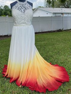 a dress on display in front of a white fence with red, yellow and orange petals