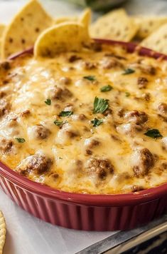 a casserole dish filled with cheese and meat surrounded by crackers on the side