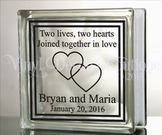 two hearts are in the center of a square glass block with an inscription that reads, two lives, two hearts joined together in love