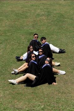 a group of young people laying on top of a lush green field next to each other