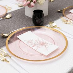 a table set with pink and gold plates, napkins, and flowers in a vase