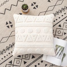 a white pillow sitting on top of a rug next to a potted plant