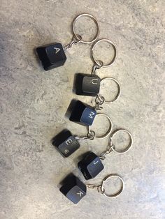 four black and gray key chains with letters on them