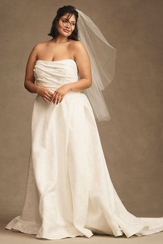 a woman in a wedding dress posing for the camera with her veil over her head