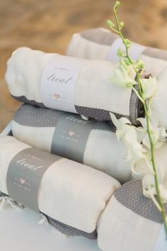 three folded towels sitting on top of each other next to a vase filled with flowers