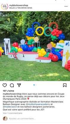 an image of a fake olympic rings in the grass with balloons on it and people standing around