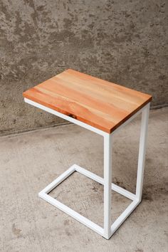 a white and wood table sitting on top of a cement floor next to a wall