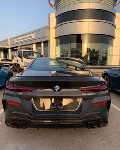 the rear end of a bmw car parked in front of a building with other cars