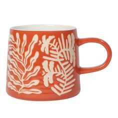 an orange and white mug with leaves on it