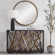 a round mirror sitting on top of a wooden cabinet next to a potted plant