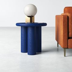 an orange chair and a blue table with a white ball on it in front of a brown couch