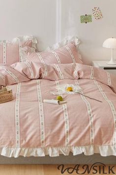 a bed with pink and white checkered bedspread, pillows and baskets on it