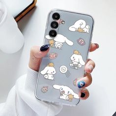 a person holding up a clear phone case with cartoon animals on it and cupcakes in the background