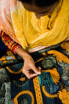 a woman is working on an embroidered cloth