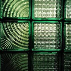 green glass blocks are arranged in a gridded pattern on the wall, reflecting light