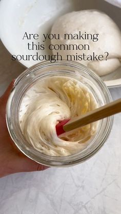 a person holding a spoon in a jar filled with whipped cream and the words are you making this common sourdough mistake?