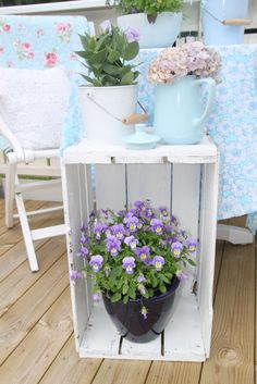 some potted plants are sitting on top of a wooden crate with flowers in it