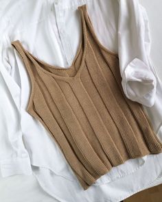 a white shirt and brown tank top on a bed