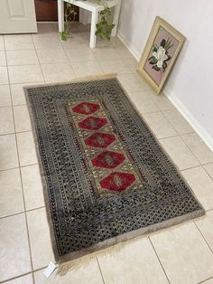 a rug is on the floor in a room with tile floors and white walls, next to a potted plant