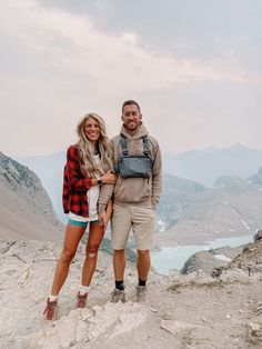 a man and woman standing on top of a mountain