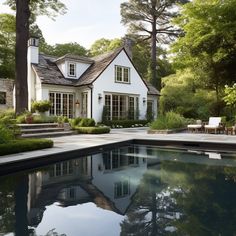 a house with a pool in front of it and trees around the back yard area