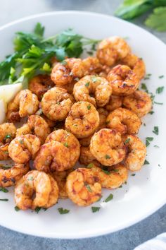 a white plate topped with cooked shrimp and garnished with parsley