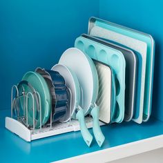 there are many dishes in the dish rack on the shelf next to the blue wall