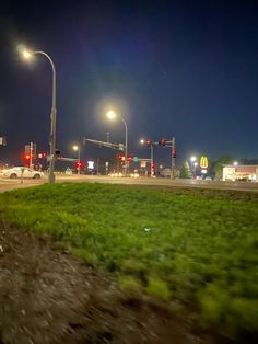 an intersection at night with traffic lights and cars driving down the road in the distance