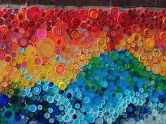 there is a colorful painting made out of plastic bottle caps on the side of a building