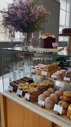 a display case filled with lots of different types of cakes and pastries in front of a window