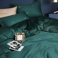 a bed with green sheets and pictures on the pillowcase, next to a blue nightstand