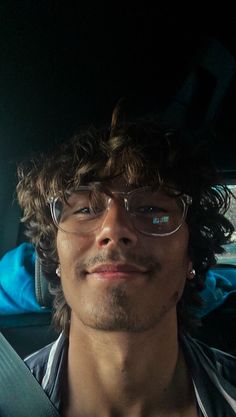 a man wearing glasses sitting in the back seat of a car