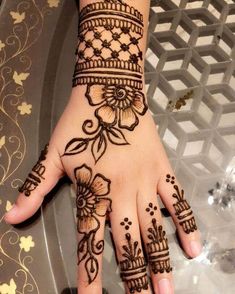 a woman's hand with henna tattoos and flowers on the palm, which is decorated