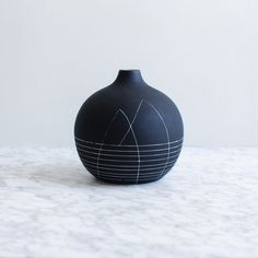 a black vase sitting on top of a white counter next to a wall and floor