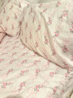 an unmade bed with pink flowers on it