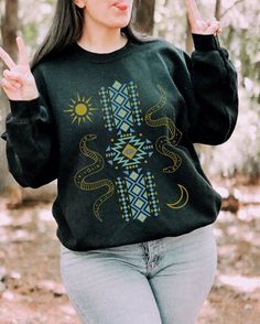 a woman in a black sweater is making the peace sign with her hands while walking through the woods