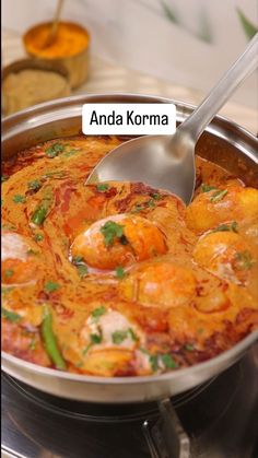 a pan filled with shrimp and vegetables on top of a stove topped with a spoon