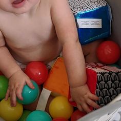 a baby in a diaper playing with balls