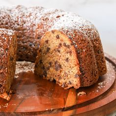 a cake that has been sliced and is on a wooden platter with powdered sugar